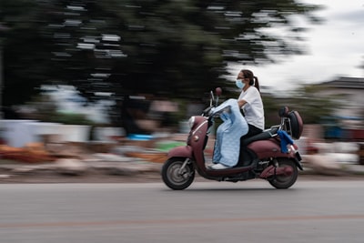 man and woman riding on red motor scooter